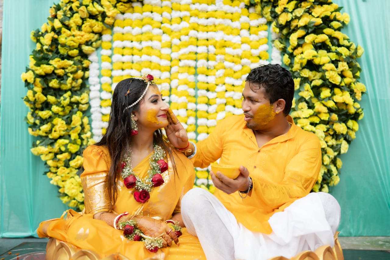 A joyful Indian couple participating in a vibrant Haldi ceremony before their wedding.